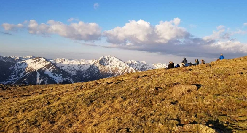 An open space sprawls in front of snow capped mountains